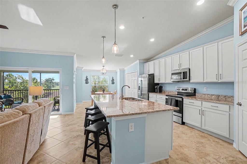 A kitchen with white cabinets, granite countertops, a center island, and light blue walls — 43051 GREENWAY BOULEVARD UNIT 823, PUNTA GORDA, FL