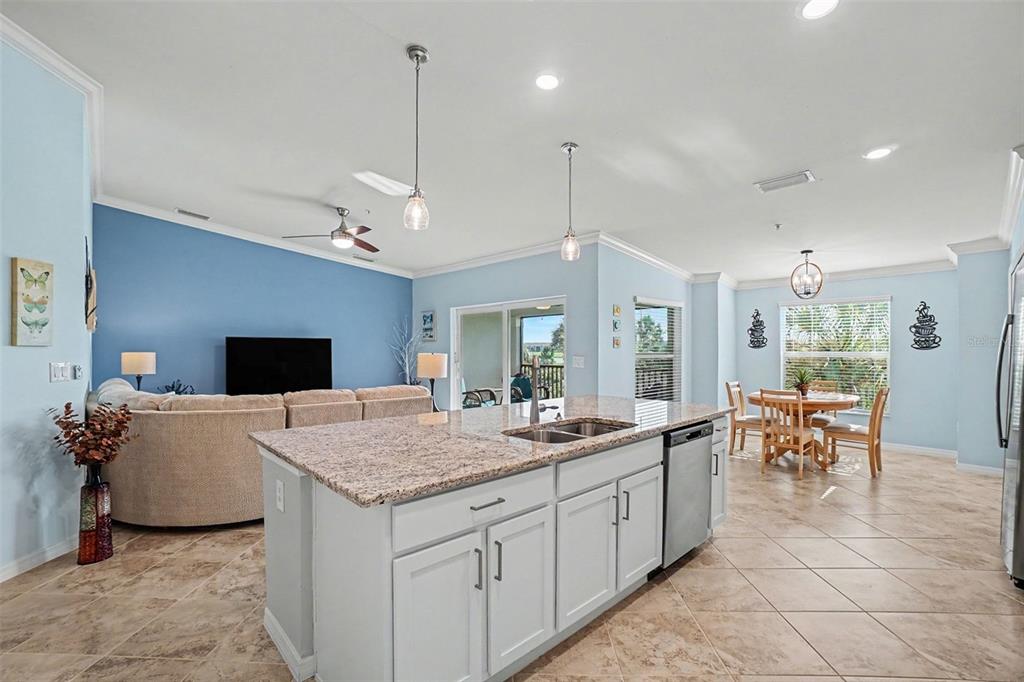 A kitchen island with granite countertops sits in an open-concept living and dining area — 43051 GREENWAY BOULEVARD UNIT 823, PUNTA GORDA, FL