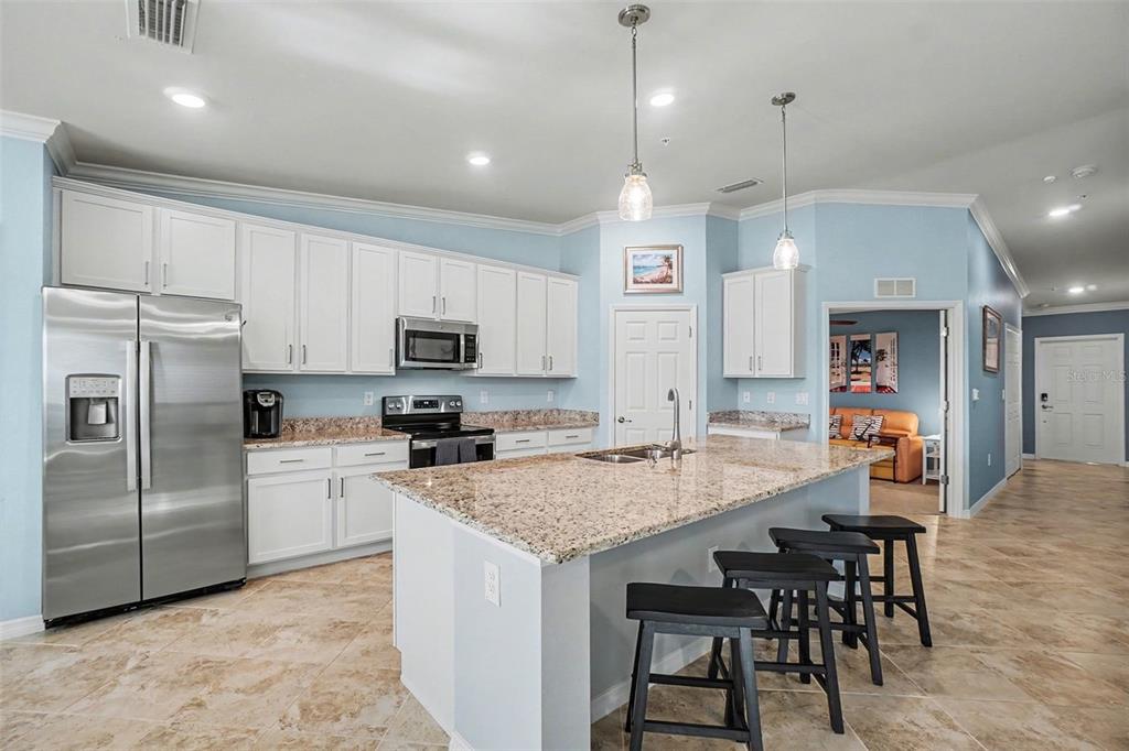 A kitchen features white cabinets, granite countertops, a stainless steel refrigerator, and a center island — 43051 GREENWAY BOULEVARD UNIT 823, PUNTA GORDA, FL