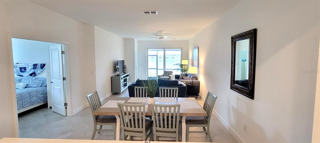 A dining area with a wooden table and chairs opens into a living room — 8787 SAINT KITTS CIRCLE, ENGLEWOOD, FL