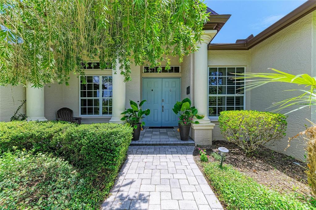 A stone walkway leads to the light blue double front doors of a stucco house — 22809 NIGHT HERON WAY, BRADENTON, FL