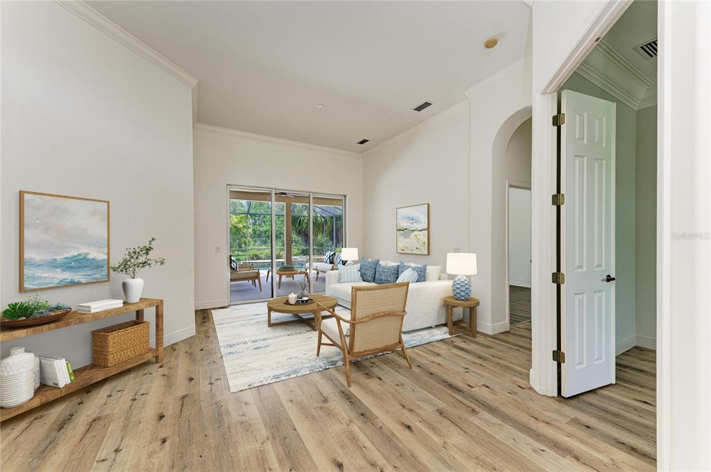 This living room features light wood flooring, a white sofa, and sliding glass doors to a patio — 22809 NIGHT HERON WAY, BRADENTON, FL