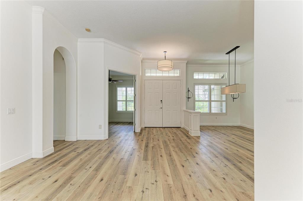 An entryway with light wood flooring, white walls, double doors, and two hanging light fixtures — 22809 NIGHT HERON WAY, BRADENTON, FL