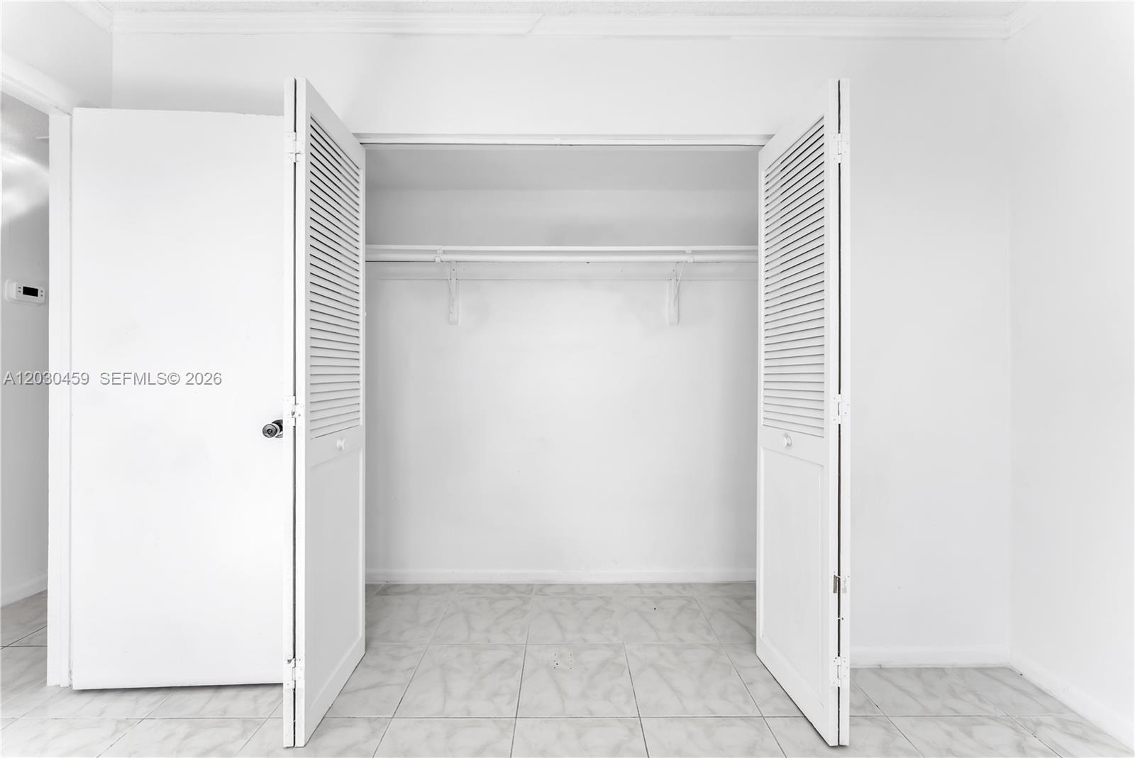 A white closet with louvered doors and a single hanging rod sits on tiled flooring — 2145 Pierce St # 305, Hollywood FL 33020, HOLLYWOOD, FL