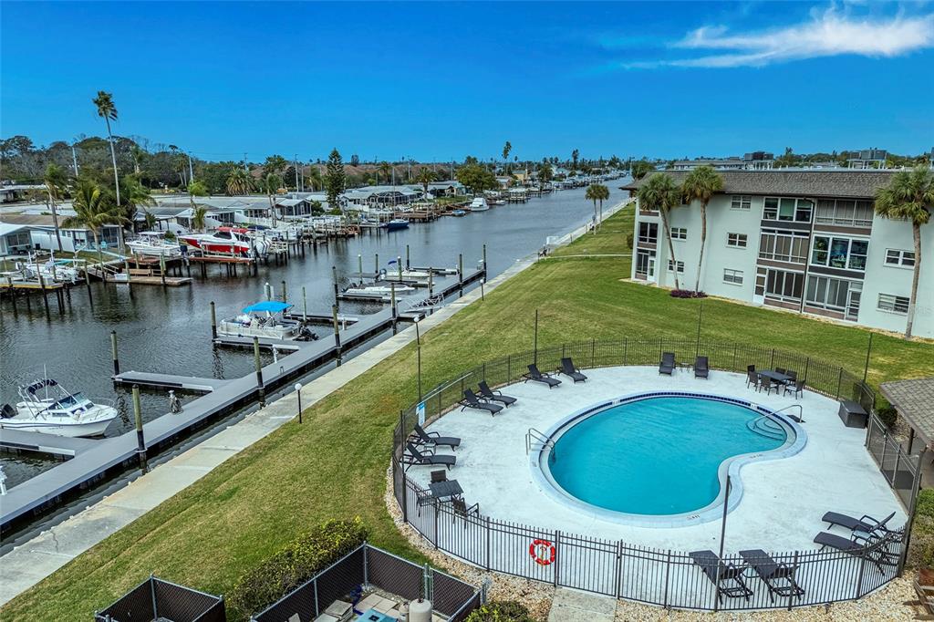 An aerial view shows a swimming pool, a boat dock, and a multi-story apartment building — 5197 SILENT LOOP UNIT 224, NEW PORT RICHEY, FL