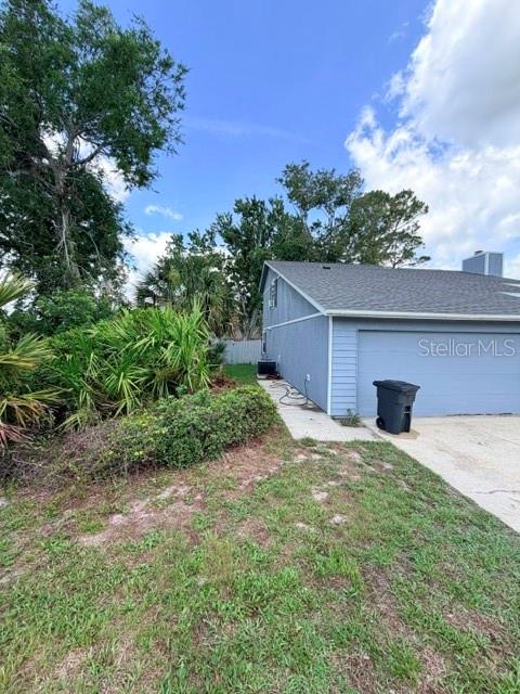 The side exterior of a blue house features a concrete walkway and a trash bin — 1194 PELLICIER COURT, PORT ORANGE, FL