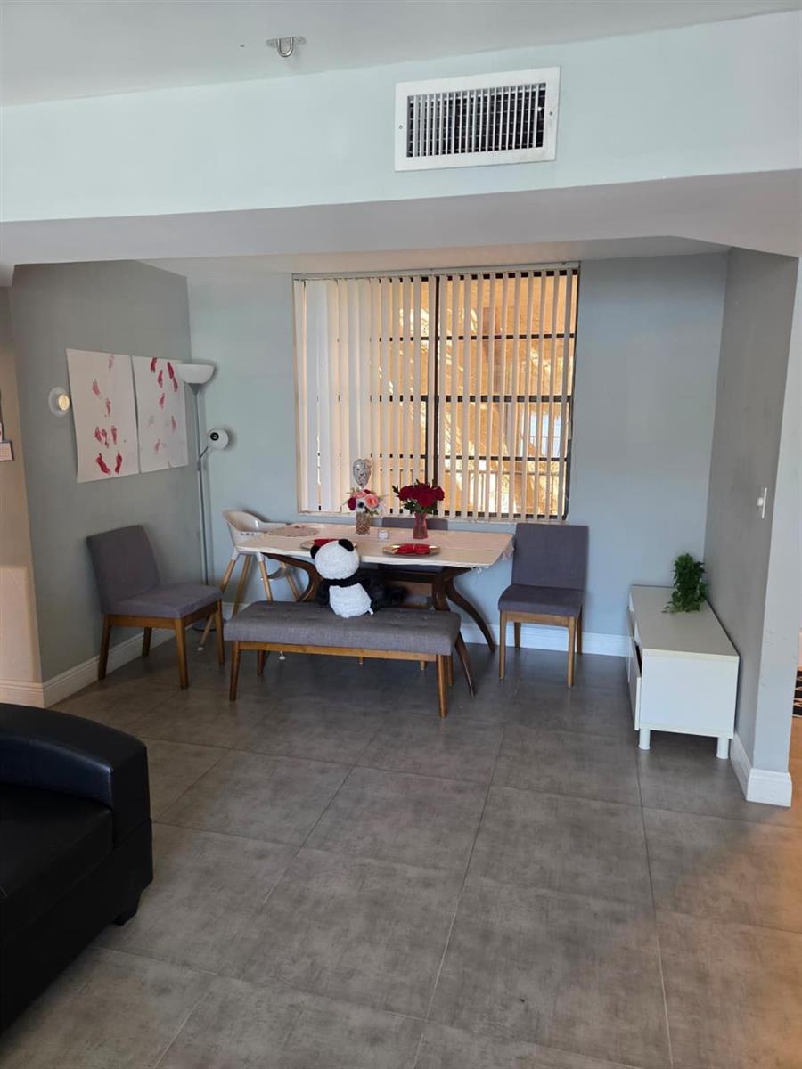 A dining area features a table with chairs and a bench on gray tile flooring — 3500 Blue Lake Drive # 304, Pompano Beach FL 33064, POMPANO BEACH, FL