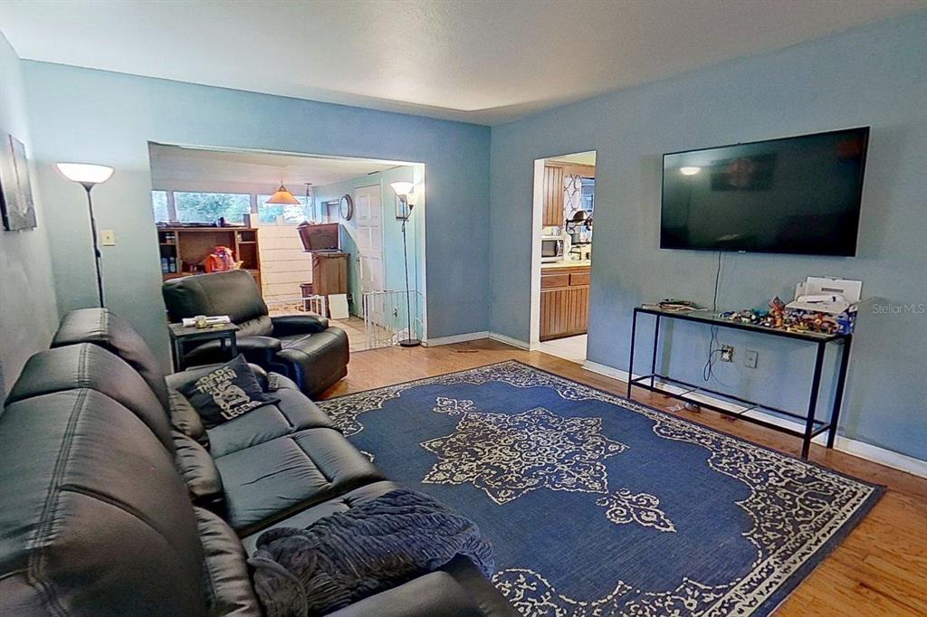 A living room features blue walls, a dark leather sofa, and a large patterned rug — 810 ORANGE VIEW DRIVE, LARGO, FL