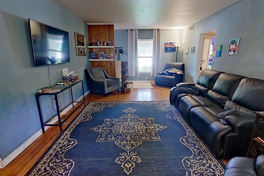 A living room with blue walls, a large area rug, a television, and leather furniture — 810 ORANGE VIEW DRIVE, LARGO, FL