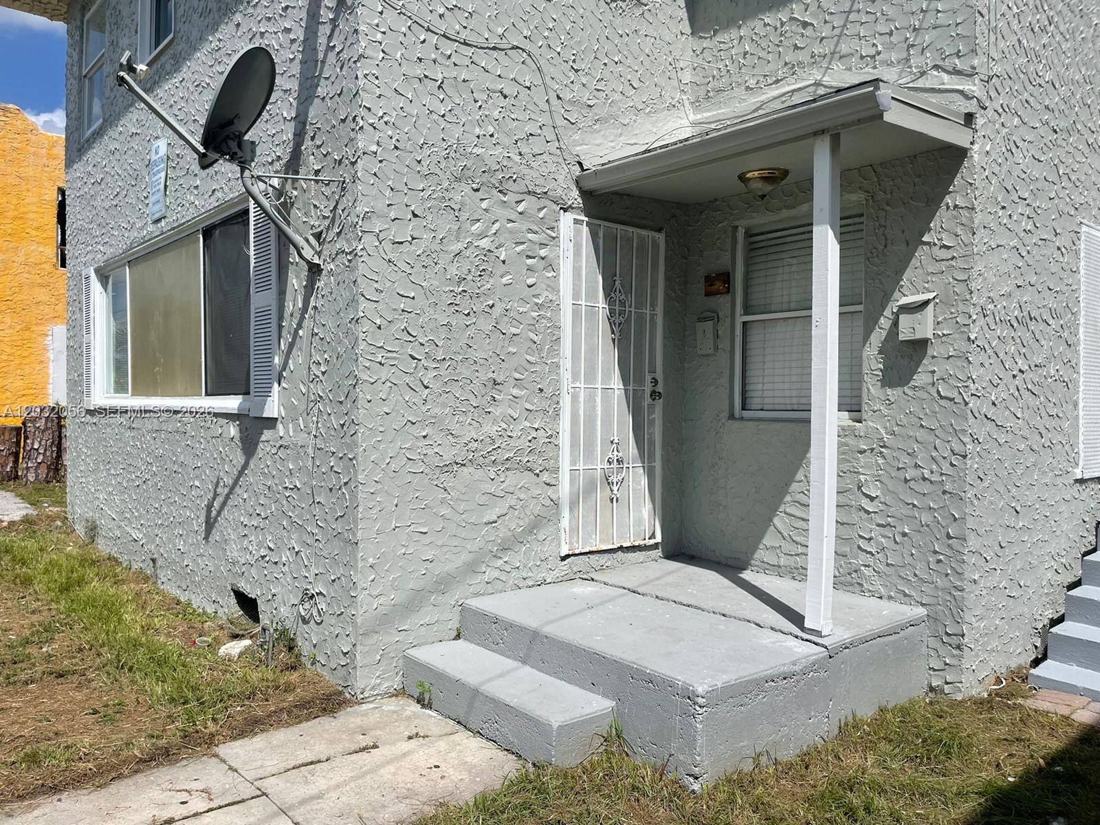 A gray stucco building exterior features a white security door, concrete steps, and a satellite dish — 817 4th St # 817, West Palm Beach FL 33401, WEST PALM BEACH, FL