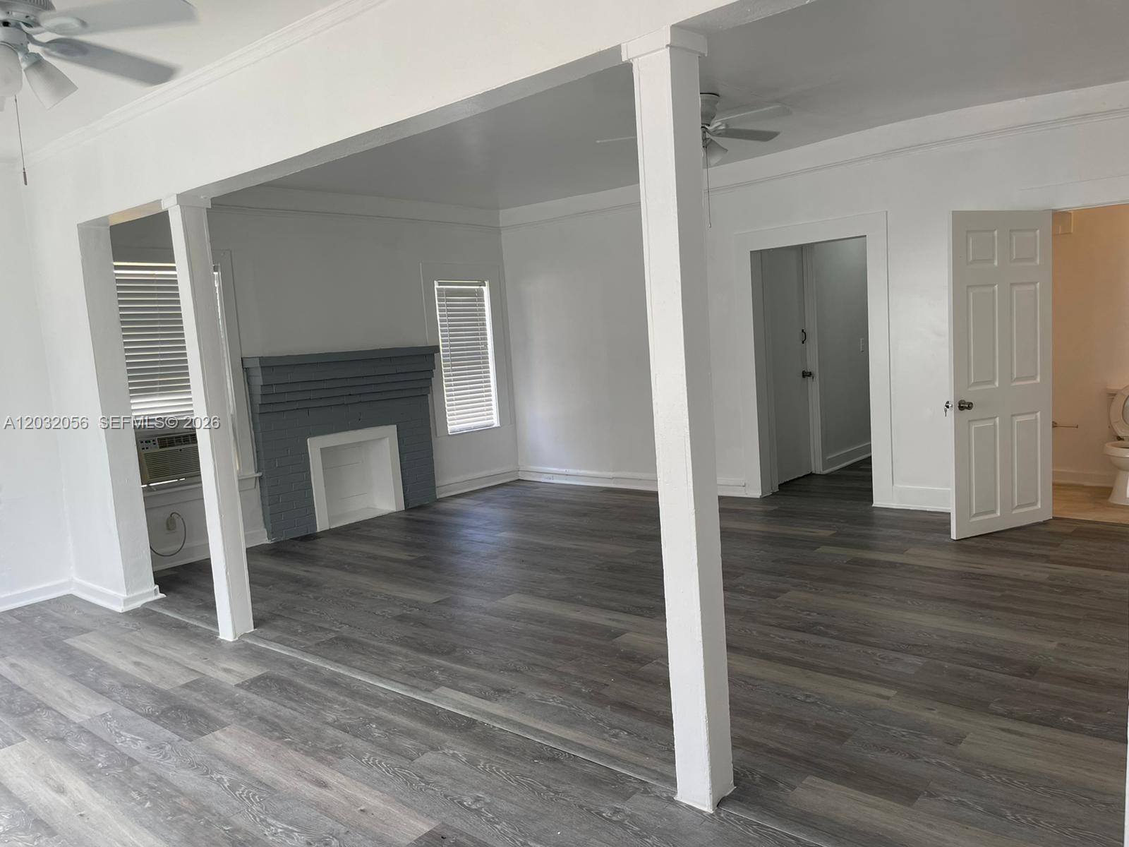An interior view shows a living area with gray wood-look flooring, white walls, and a fireplace — 817 4th St # 817, West Palm Beach FL 33401, WEST PALM BEACH, FL