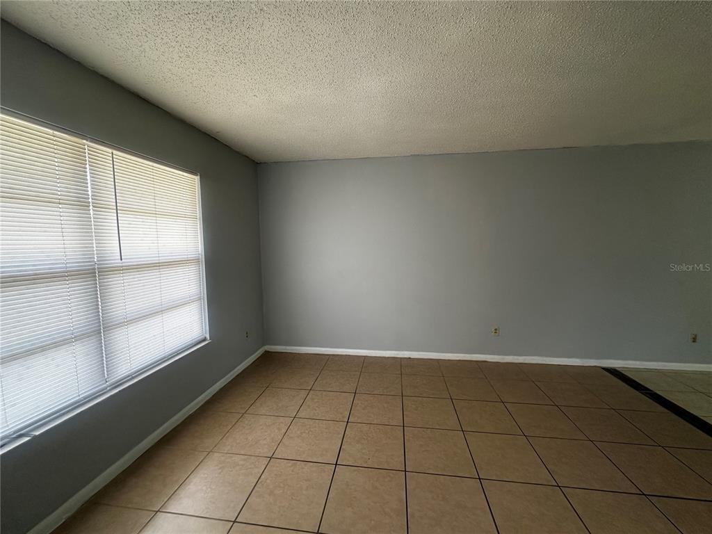 An empty room features gray walls, tan tile flooring, and a window with white blinds — 455 WATER ROAD, OCALA, FL