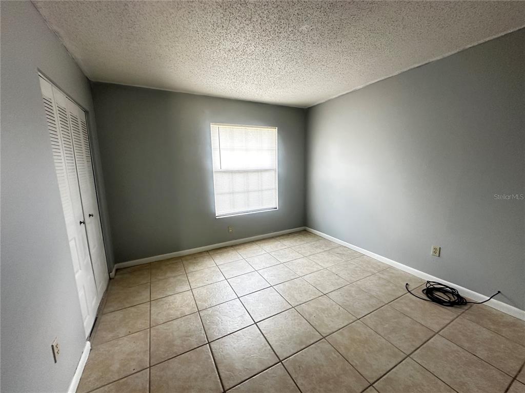 An empty bedroom features gray walls, a tiled floor, a window with blinds, and closet doors — 455 WATER ROAD, OCALA, FL