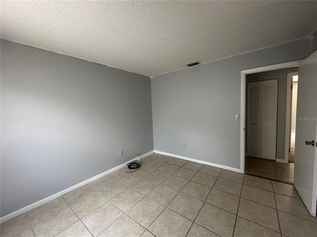 An empty room features gray walls, light-colored tile flooring, and a doorway leading to a closet — 455 WATER ROAD, OCALA, FL