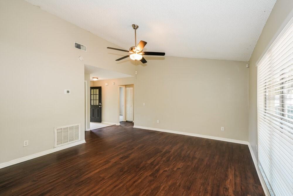 A living room with vaulted ceilings, a ceiling fan, and dark wood-look flooring — 1670 PALM LEAF DRIVE, BRANDON, FL