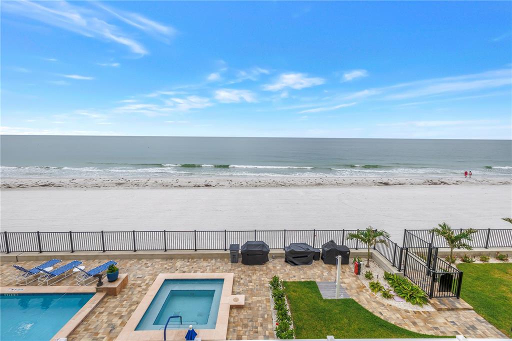 A high-angle view of a beachside patio with a pool, hot tub, and ocean view — 16750 GULF BOULEVARD UNIT 313, NORTH REDINGTON BEACH, FL