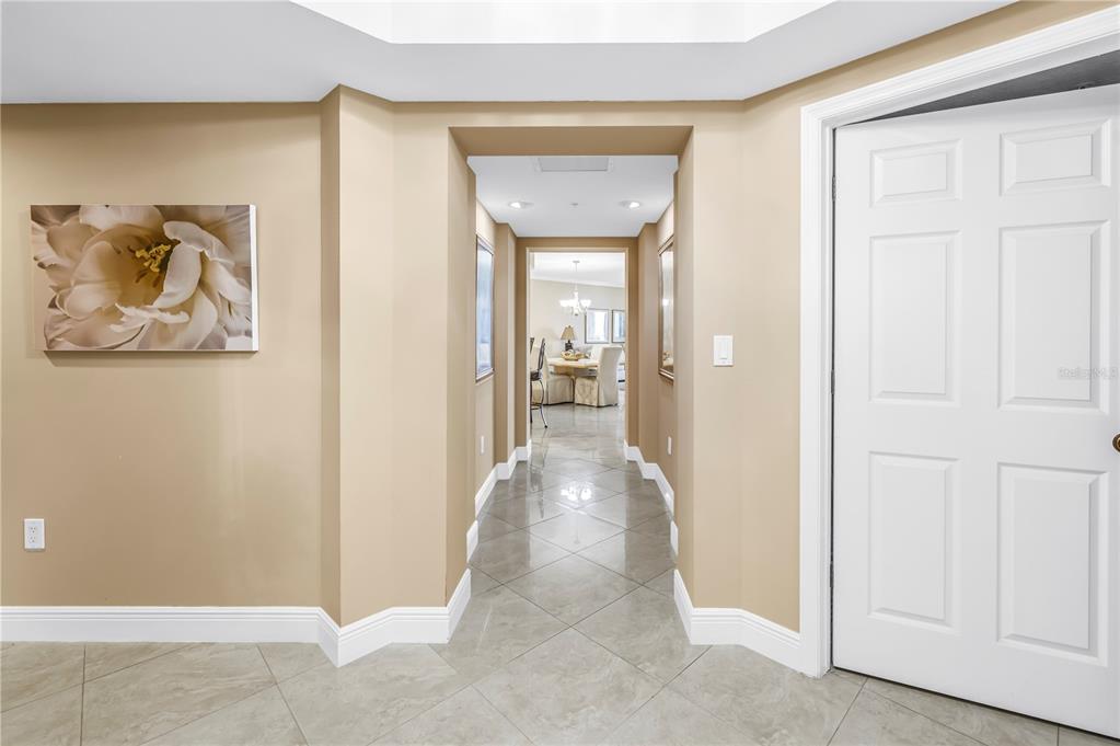 A hallway with light-colored walls and tile flooring leads to a dining area — 16750 GULF BOULEVARD UNIT 313, NORTH REDINGTON BEACH, FL