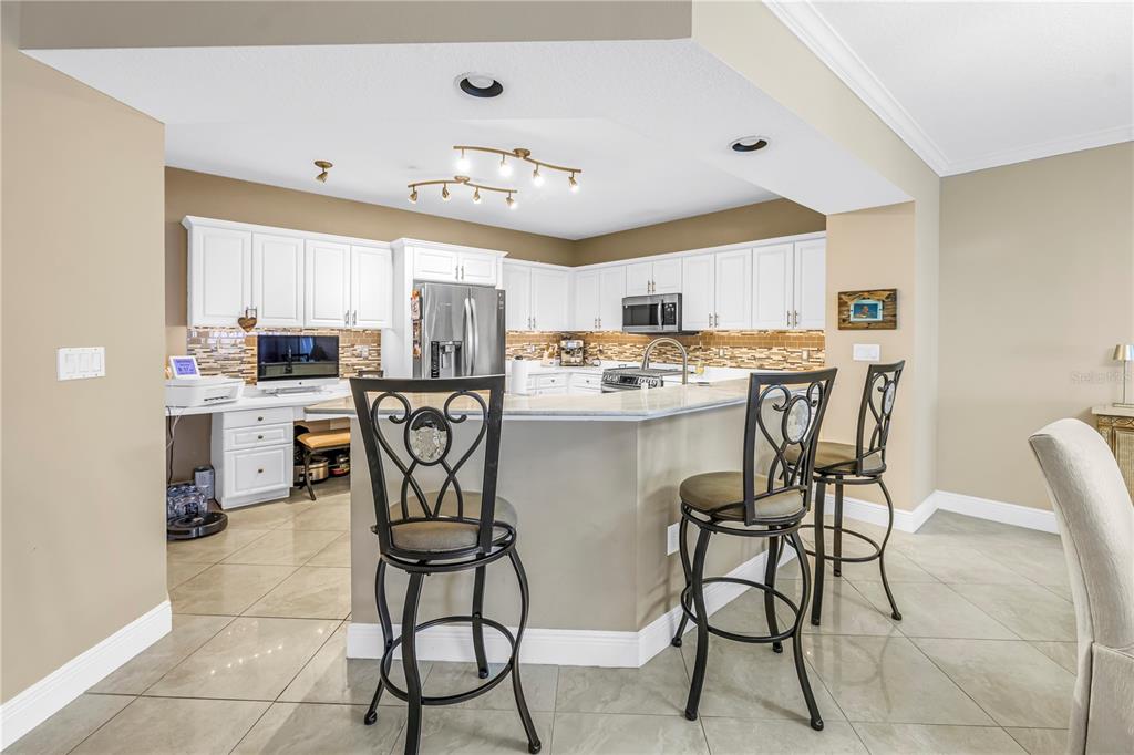 A kitchen features white cabinets, a breakfast bar with two stools, and tile flooring — 16750 GULF BOULEVARD UNIT 313, NORTH REDINGTON BEACH, FL
