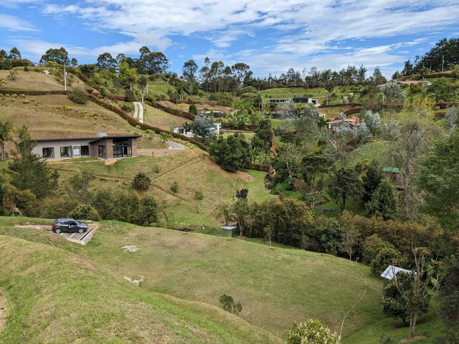 An elevated view of a modern house on a grassy hillside with a parked car — 00000 Vereda Santa Ana, FL