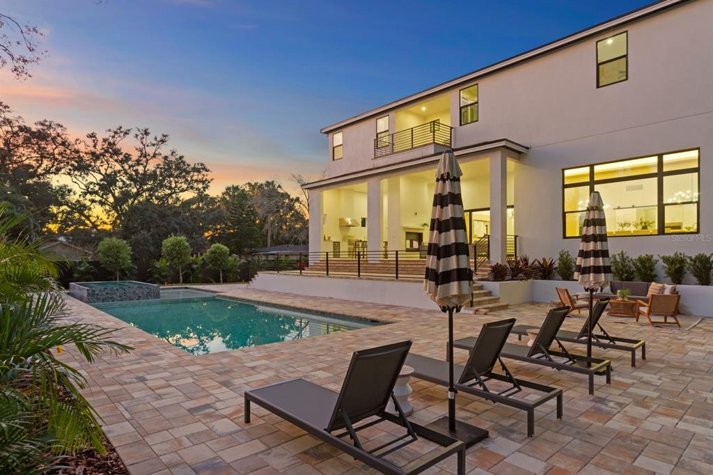 A modern two-story house with a pool, patio, and lounge chairs at sunset — 4624 W SAN JOSE STREET, TAMPA, FL