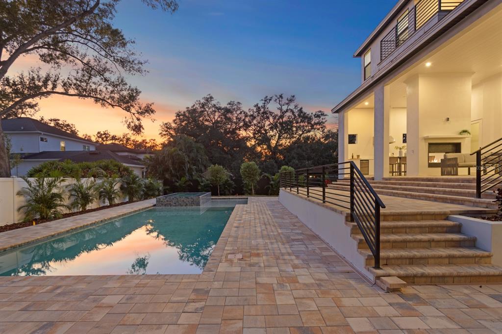 A backyard features a swimming pool, stone patio, and a covered porch with outdoor stairs — 4624 W SAN JOSE STREET, TAMPA, FL