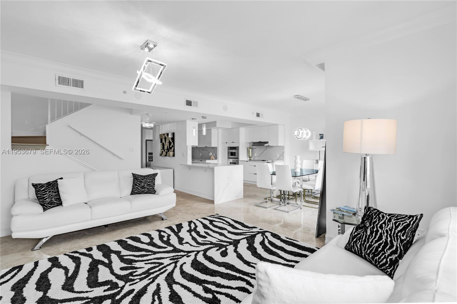 A modern living and dining area features white furniture, zebra-print accents, and marble flooring — 99 SE Mizner Blvd, Boca Raton FL 33432, BOCA RATON, FL