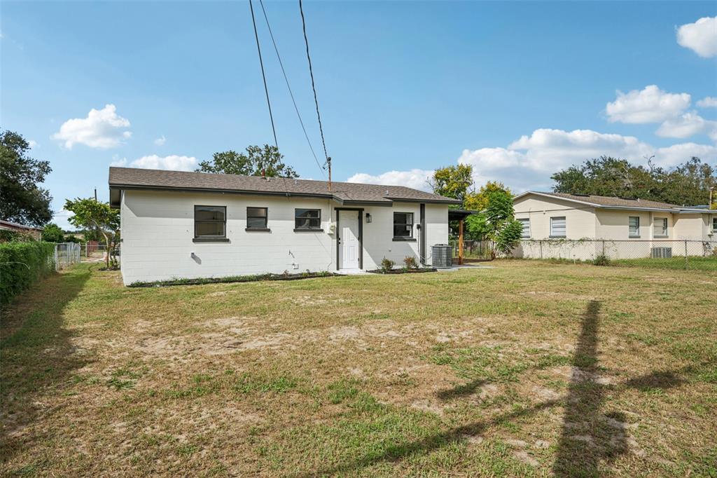 The exterior of a white, single-story house with a large, grassy backyard — 2633 ROYAL DRIVE, LAKELAND, FL