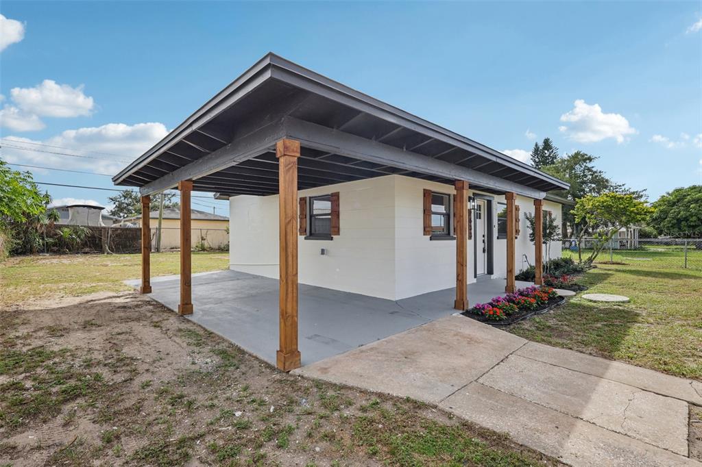 A single-story house with a large covered carport and wooden support posts — 2633 ROYAL DRIVE, LAKELAND, FL