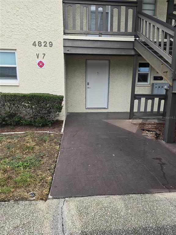 The exterior of a multi-story apartment building features a ground-level entrance, stairs, and a balcony — 4829 ONYX LANE UNIT 101, NEW PORT RICHEY, FL