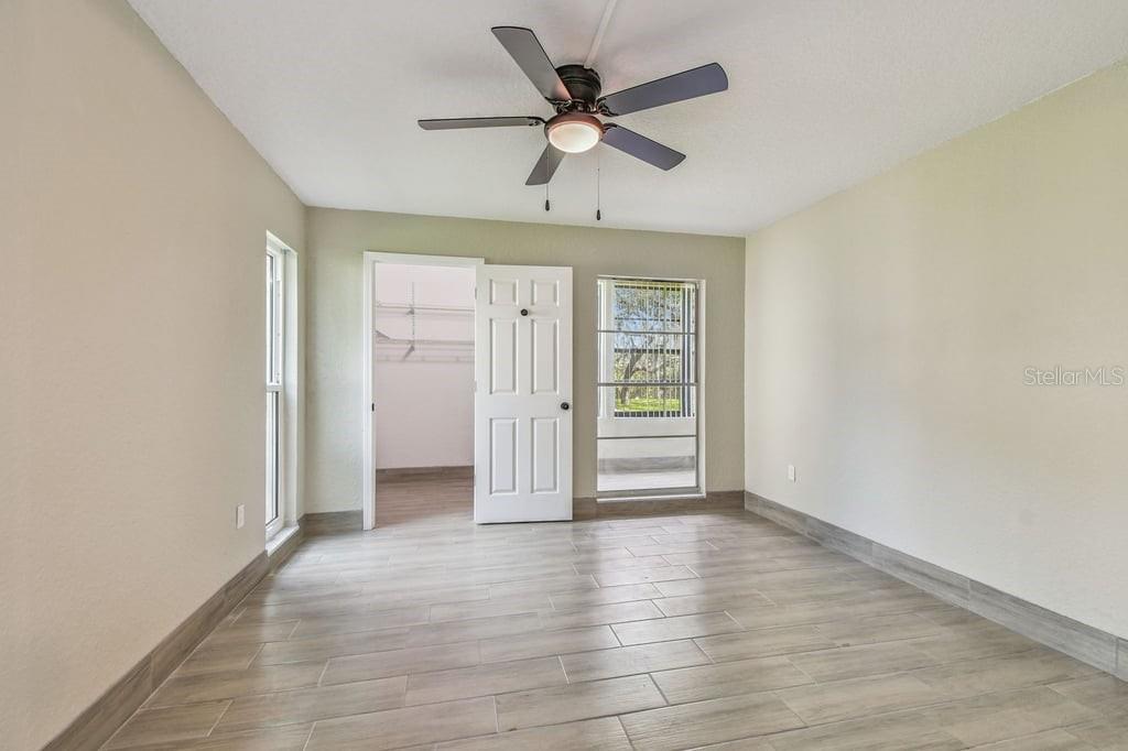 An empty room features light-colored tile flooring, a ceiling fan, and a walk-in closet — 4829 ONYX LANE UNIT 101, NEW PORT RICHEY, FL