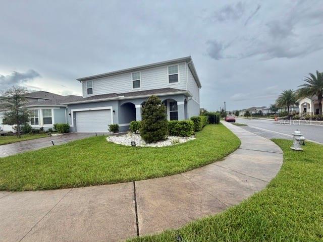 A two-story house with light gray siding and a white garage sits beside a sidewalk — 5660 ARBORVISTA DRIVE, ST CLOUD, FL
