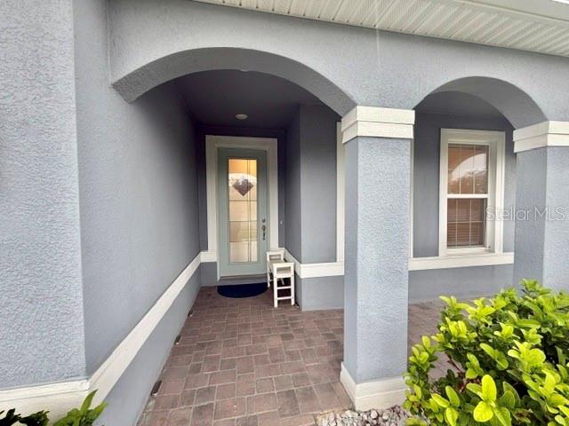 A covered entryway features a light blue door, arched columns, and a paved porch floor — 5660 ARBORVISTA DRIVE, ST CLOUD, FL