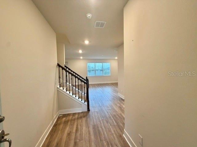 A foyer with wood-look flooring leads to a staircase and an open living area — 5660 ARBORVISTA DRIVE, ST CLOUD, FL