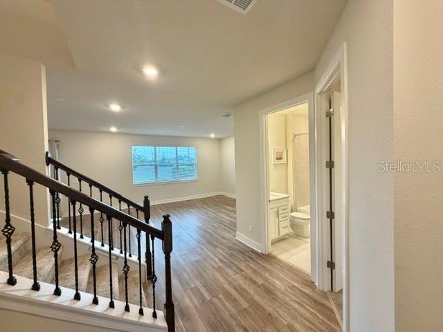 A staircase with iron railings leads to an open living area with wood-look flooring — 5660 ARBORVISTA DRIVE, ST CLOUD, FL