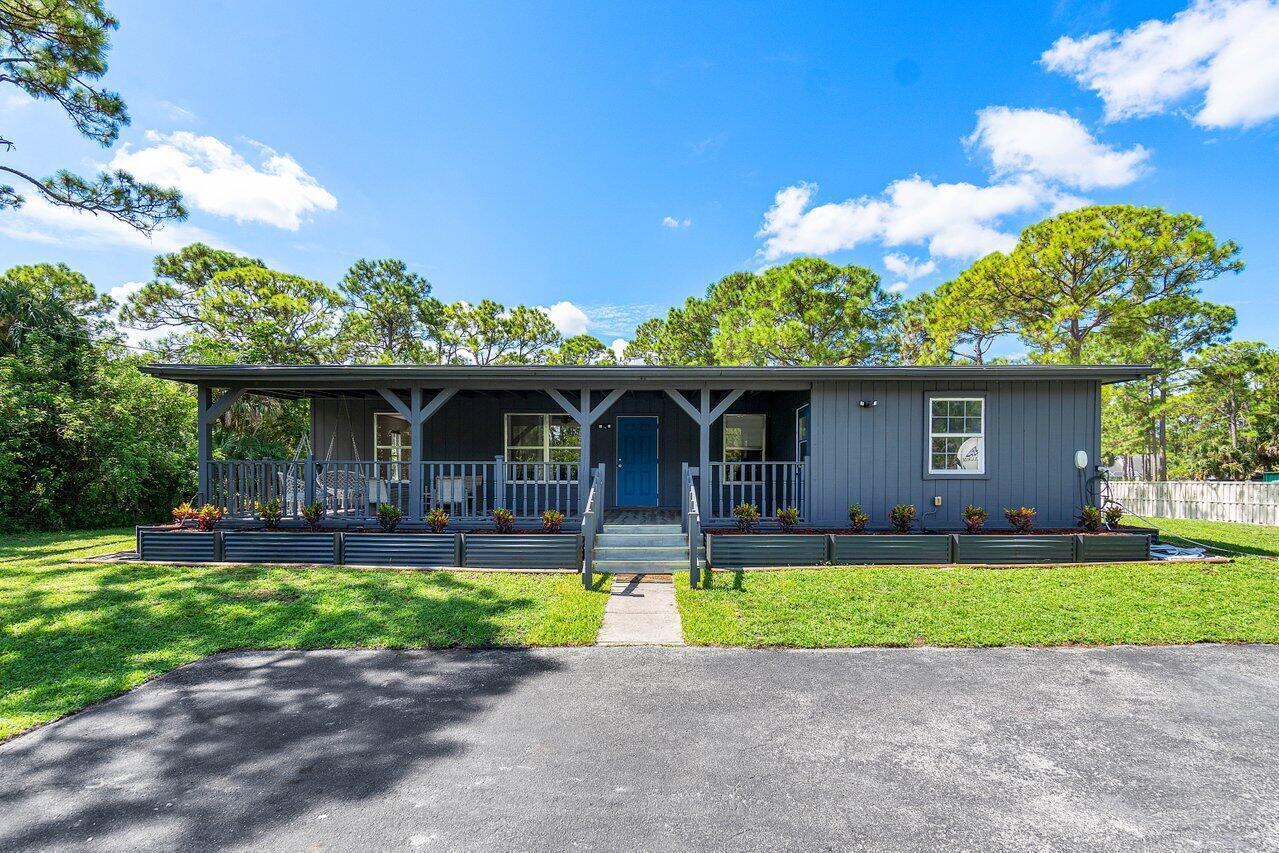 A single-story gray house with a covered front porch and a paved driveway — 11448 N 68th St Street N, FL 33412, FL