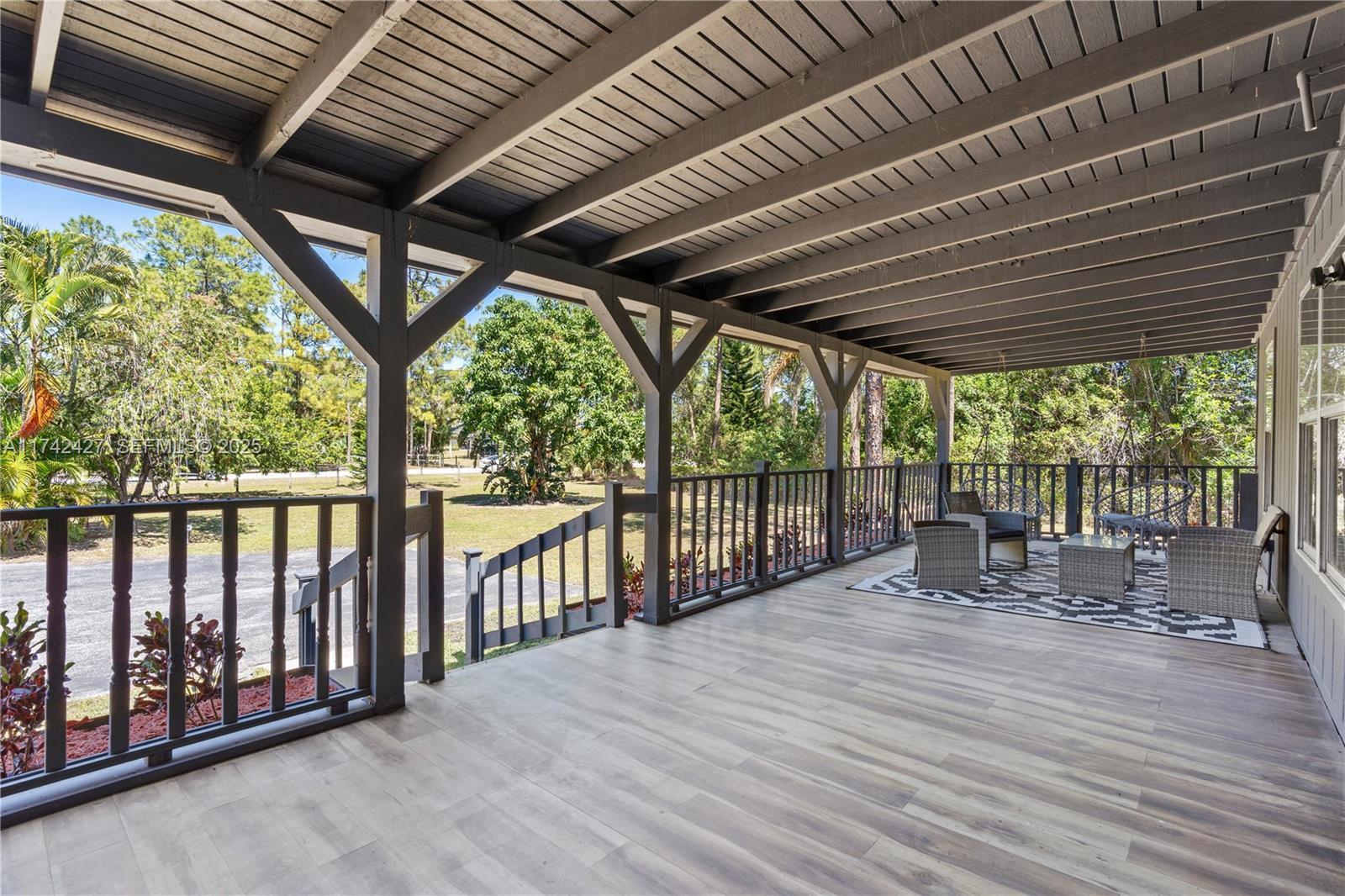 A covered outdoor deck features wood-look flooring, a railing, and patio furniture — 11448 N 68th St Street N, FL 33412, FL
