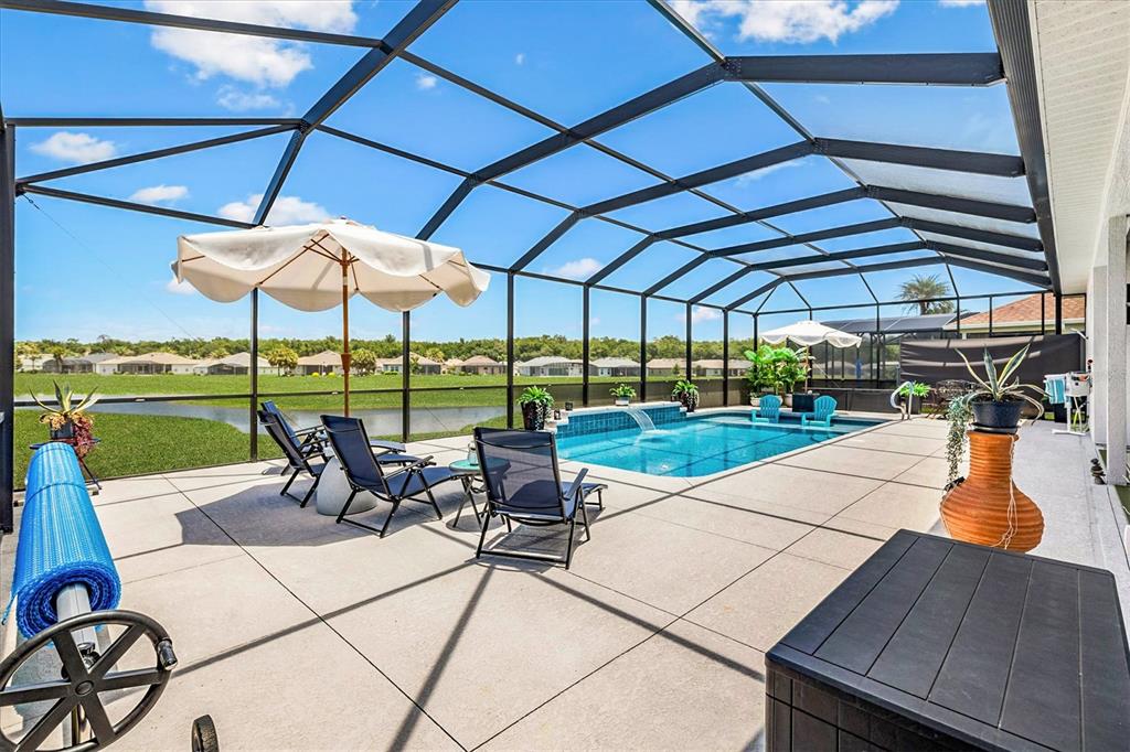 A screened-in pool patio features a swimming pool, lounge chairs, and a view of water — 17585 SE 122ND TERRACE, SUMMERFIELD, FL