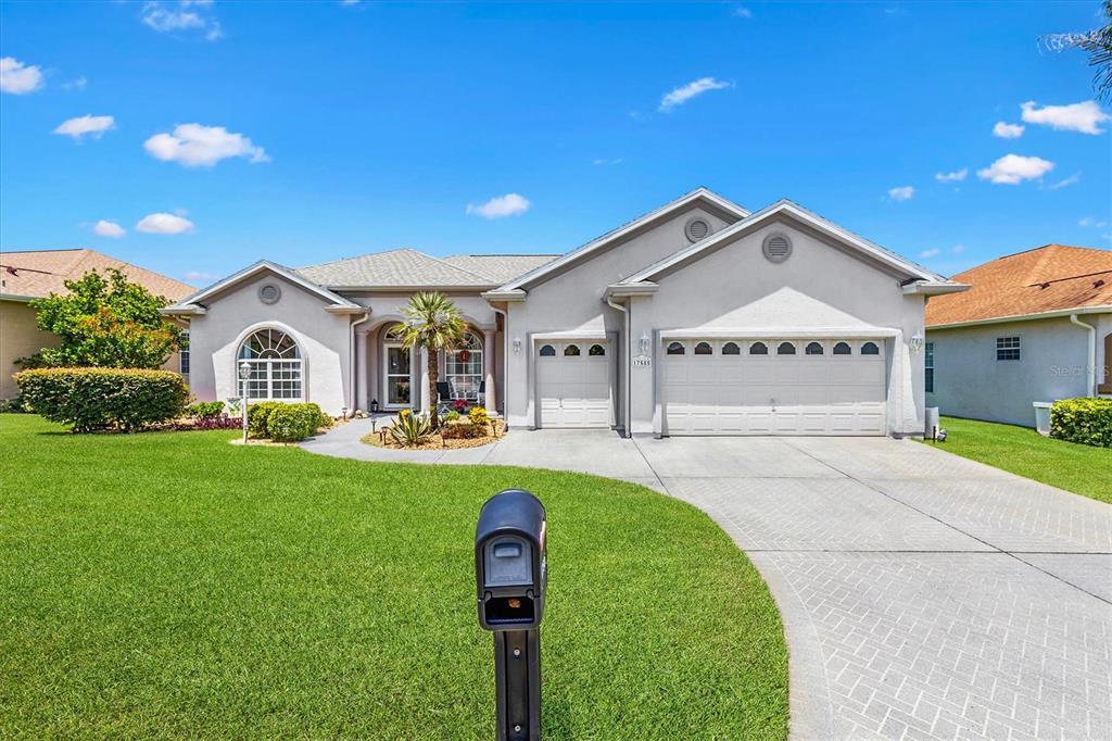 A single-story house with a light-colored stucco exterior, a three-car garage, and a front lawn — 17585 SE 122ND TERRACE, SUMMERFIELD, FL