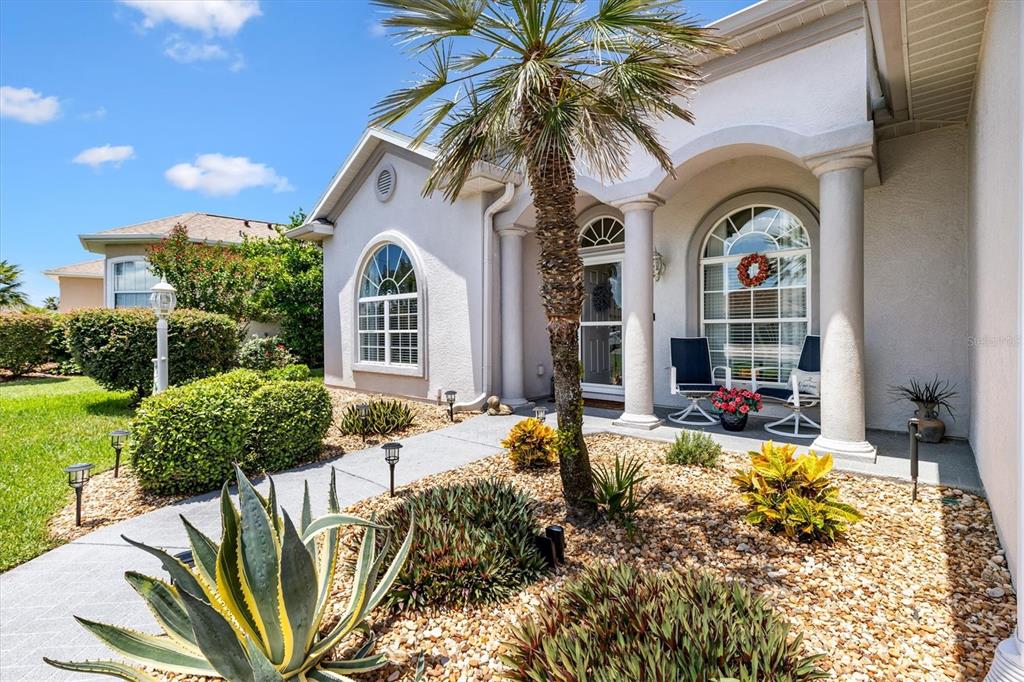 The exterior of a house features a palm tree, arched windows, and a covered entryway — 17585 SE 122ND TERRACE, SUMMERFIELD, FL