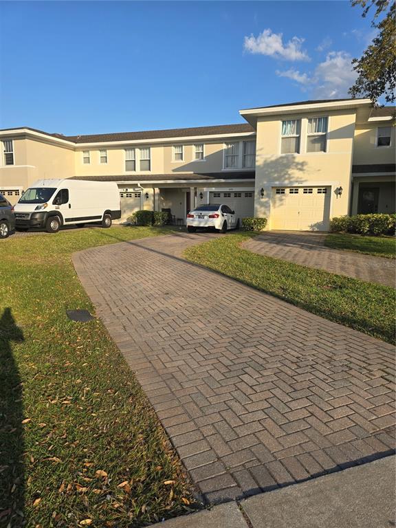 A paved driveway leads to a two-story townhouse complex with a white van and car — 2039 CYPRESS BAY BOULEVARD, KISSIMMEE, FL