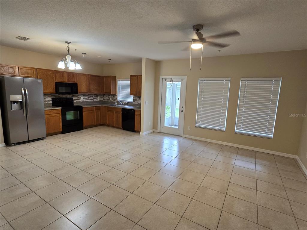 A kitchen with wood cabinets, stainless steel appliances, and tile flooring opens to a living area — 2039 CYPRESS BAY BOULEVARD, KISSIMMEE, FL