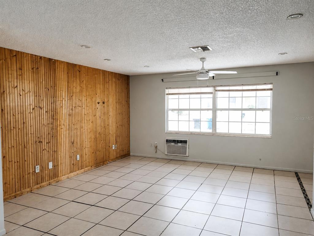 A room with light-colored floor tiles, a wood-paneled wall, and a window with an air conditioner — 765 HIGHLAND DRIVE, ORANGE CITY, FL