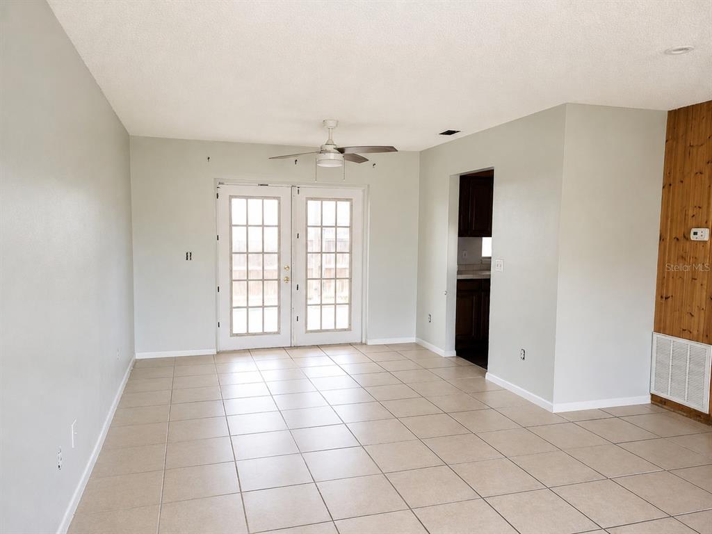 A room with light-colored tile flooring, white walls, a ceiling fan, and French doors — 765 HIGHLAND DRIVE, ORANGE CITY, FL