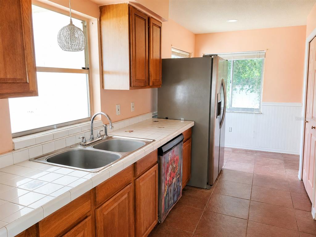A kitchen with wood cabinets, tiled countertops, a double sink, and stainless steel appliances — 765 HIGHLAND DRIVE, ORANGE CITY, FL