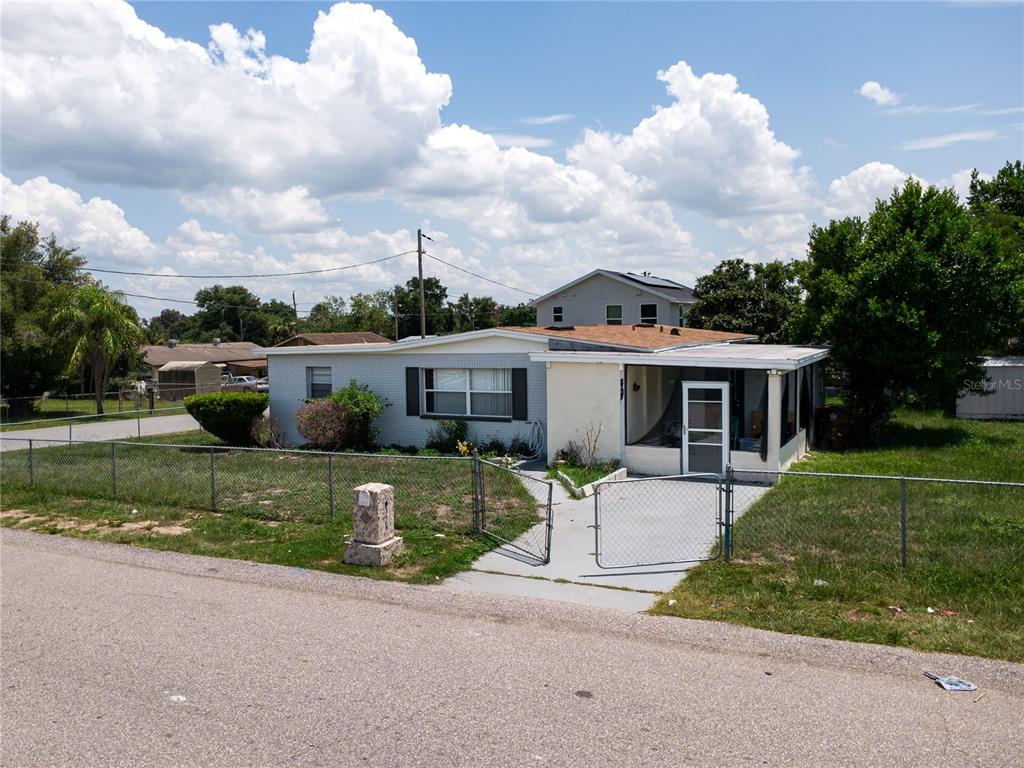 A single-story house with a gray brick exterior, a screened-in porch, and a chain-link fence — 1125 AVENUE L, HAINES CITY, FL