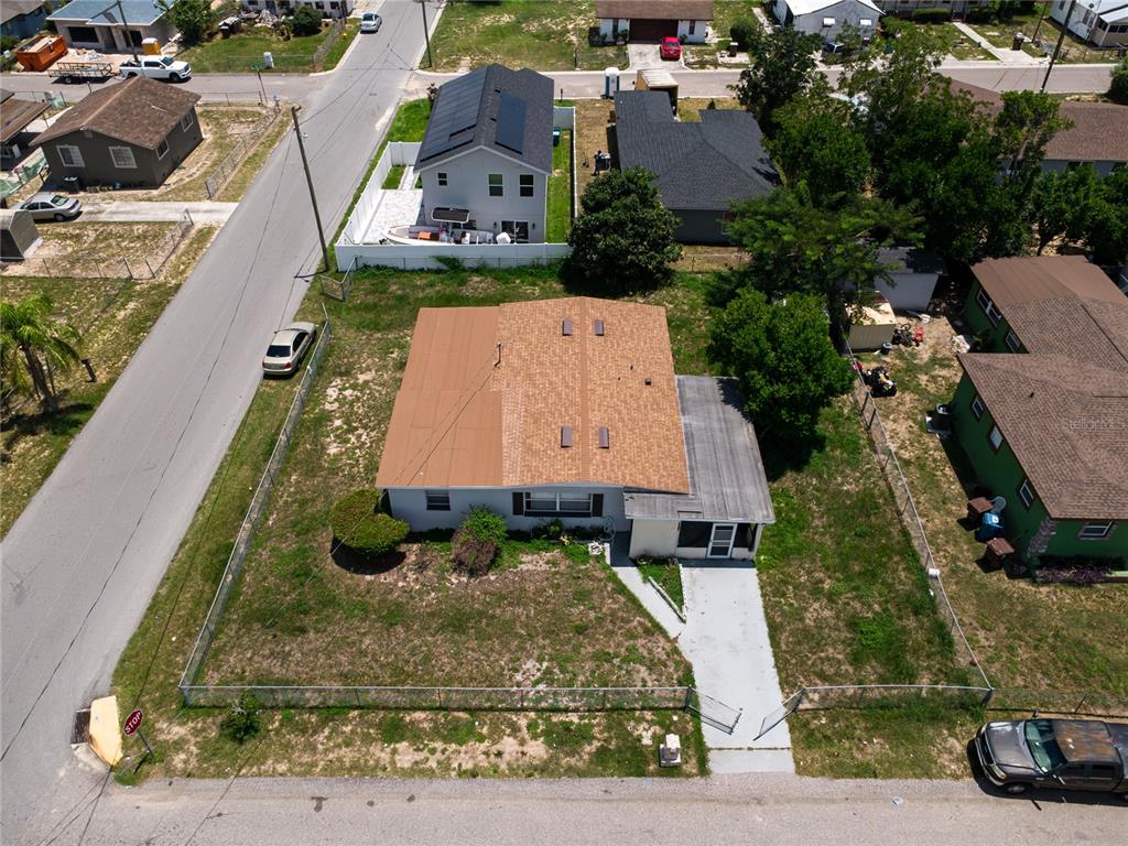 An aerial view shows a single-story house with a brown roof and a fenced yard — 1125 AVENUE L, HAINES CITY, FL