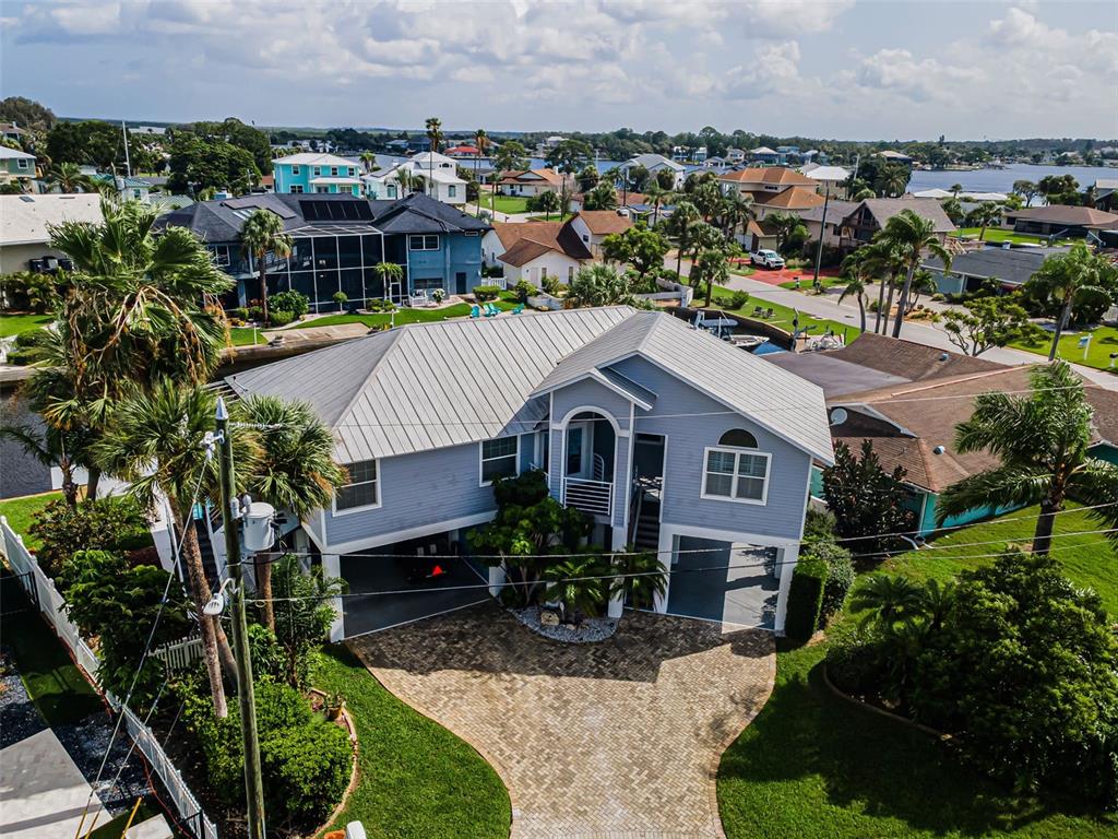 A two-story house with gray siding, a paved driveway, and a covered ground-level parking area — 8001 BRIGHTON DRIVE, PORT RICHEY, FL