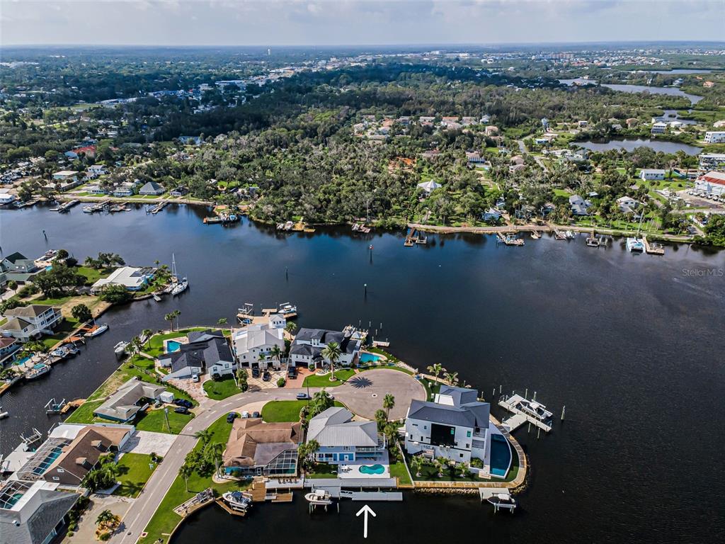 A kidney-shaped swimming pool sits on a patio overlooking a canal at sunset — 8001 BRIGHTON DRIVE, PORT RICHEY, FL