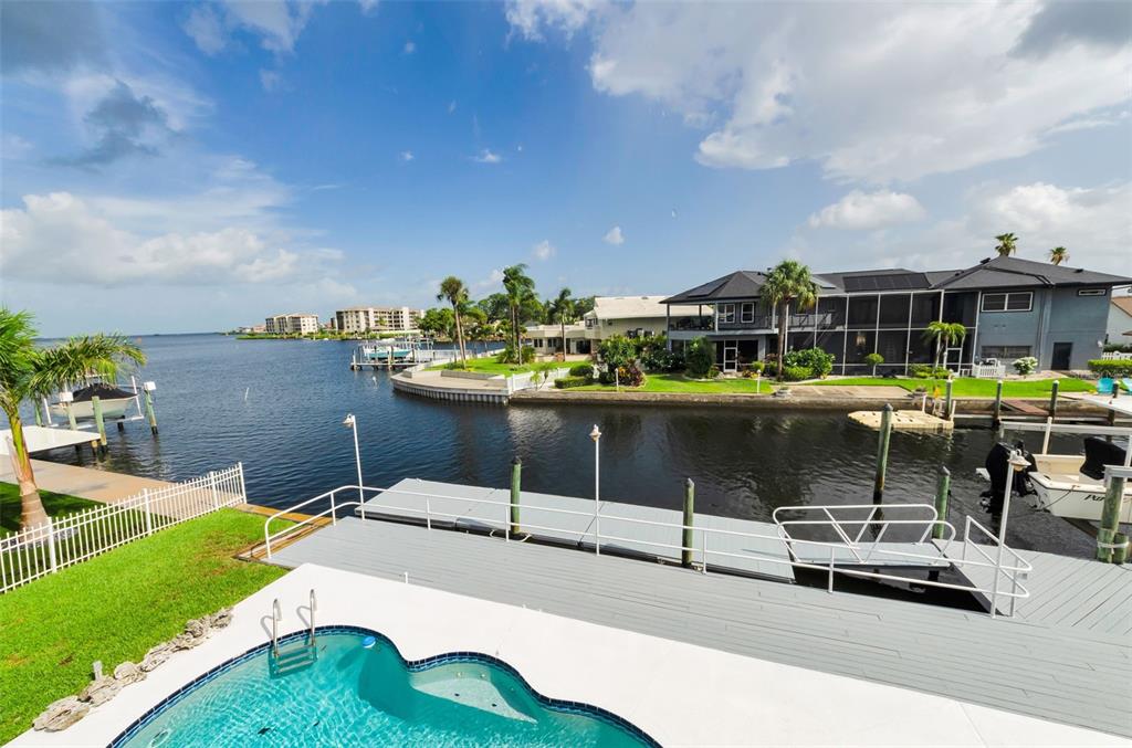 A swimming pool overlooks a canal at sunset with a full moon in the sky — 8001 BRIGHTON DRIVE, PORT RICHEY, FL