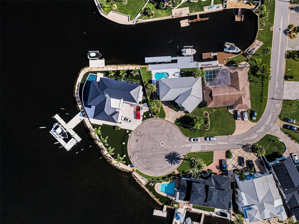 A grassy backyard leads to a concrete dock with patio furniture and a docked boat — 8001 BRIGHTON DRIVE, PORT RICHEY, FL